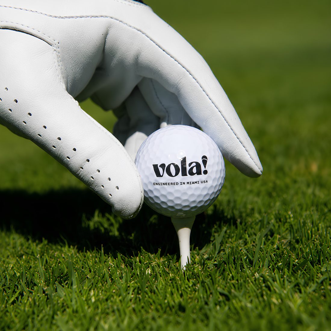 Tay đeo găng đặt bóng golf 3 lớp vola! lên tee trên sân cỏ