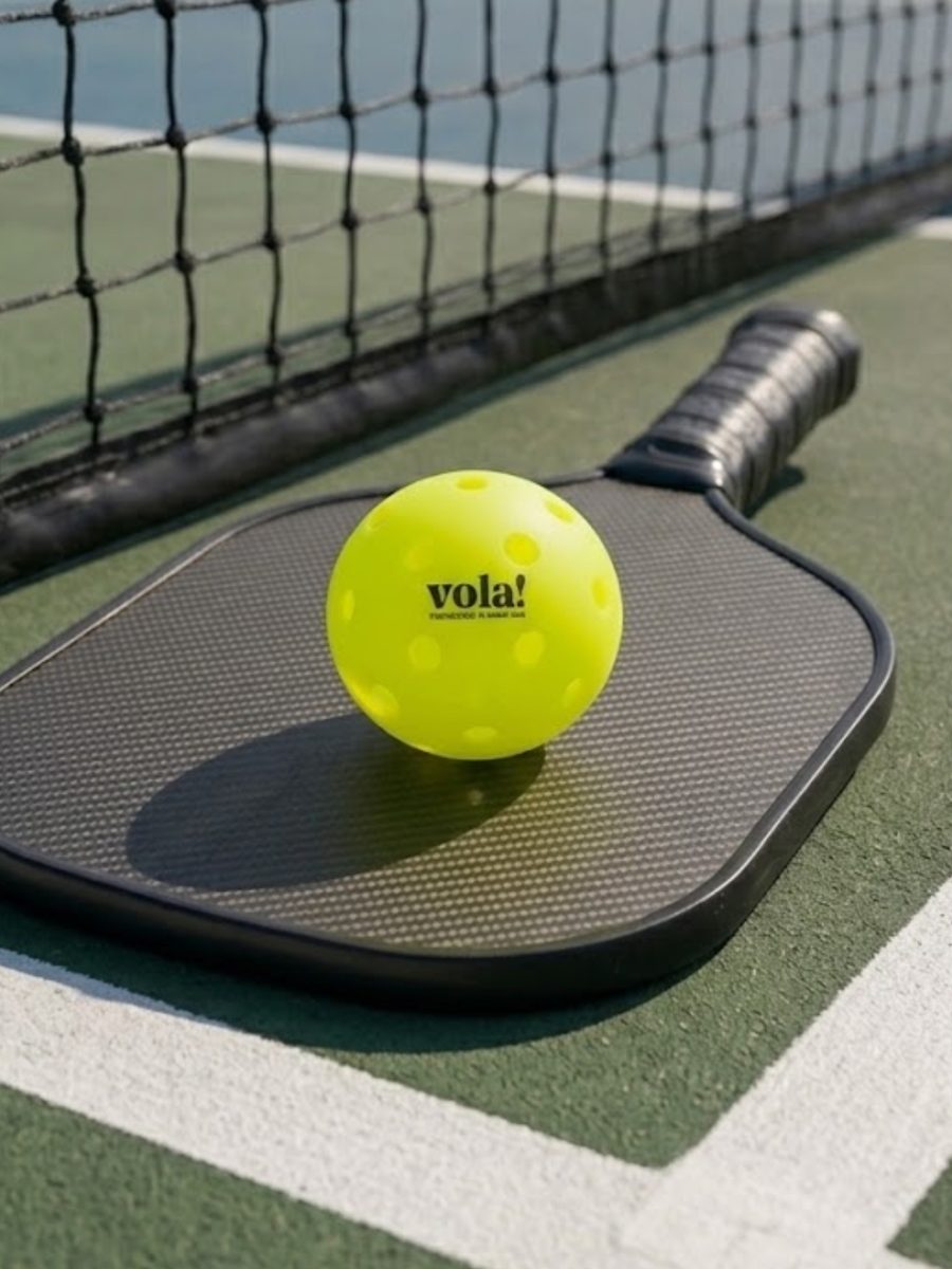 Bóng pickleball vola! trên vợt cạnh lưới sân ngoài trời